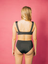 Model wears black tie front closure bikini top. Bikini is made sustainably from recycled fishnets 